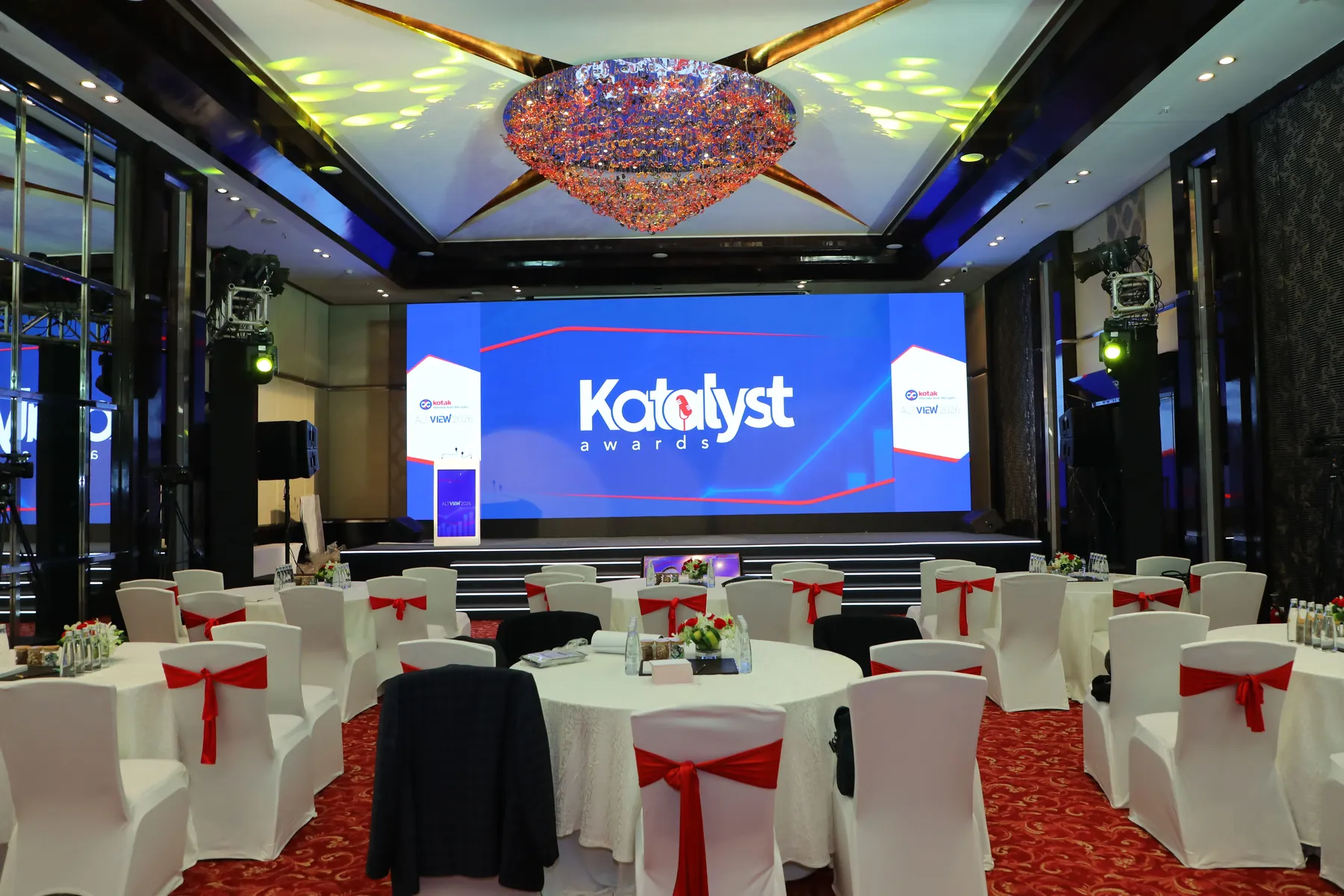 A banquet hall with round tables and a large Katalyst Awards stage screen.