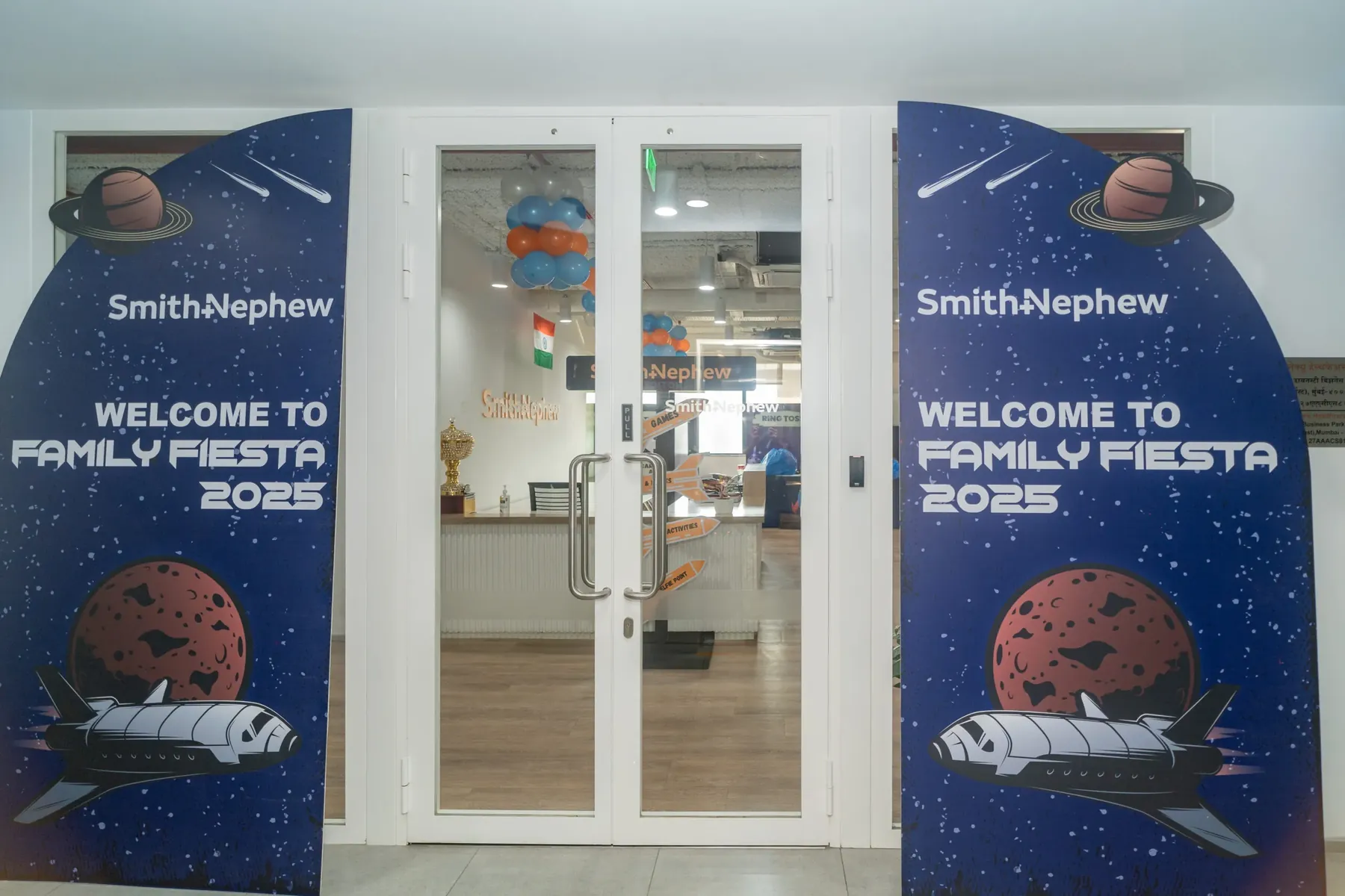 Glass doors flanked by Smith+Nephew Family Fiesta 2025 space-themed welcome banners.