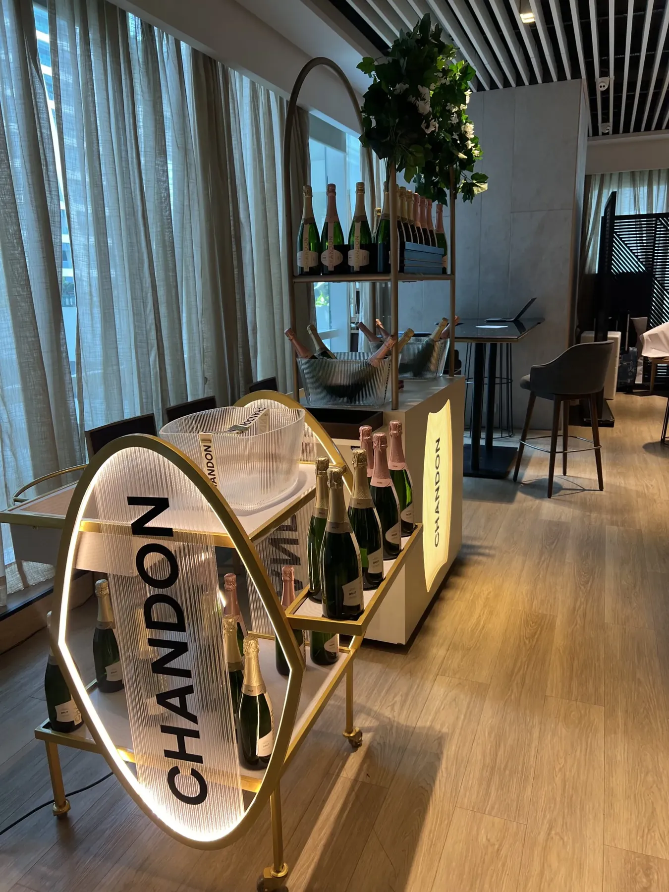 An illuminated Chandon-branded bar cart displaying bottles of sparkling wine indoors.