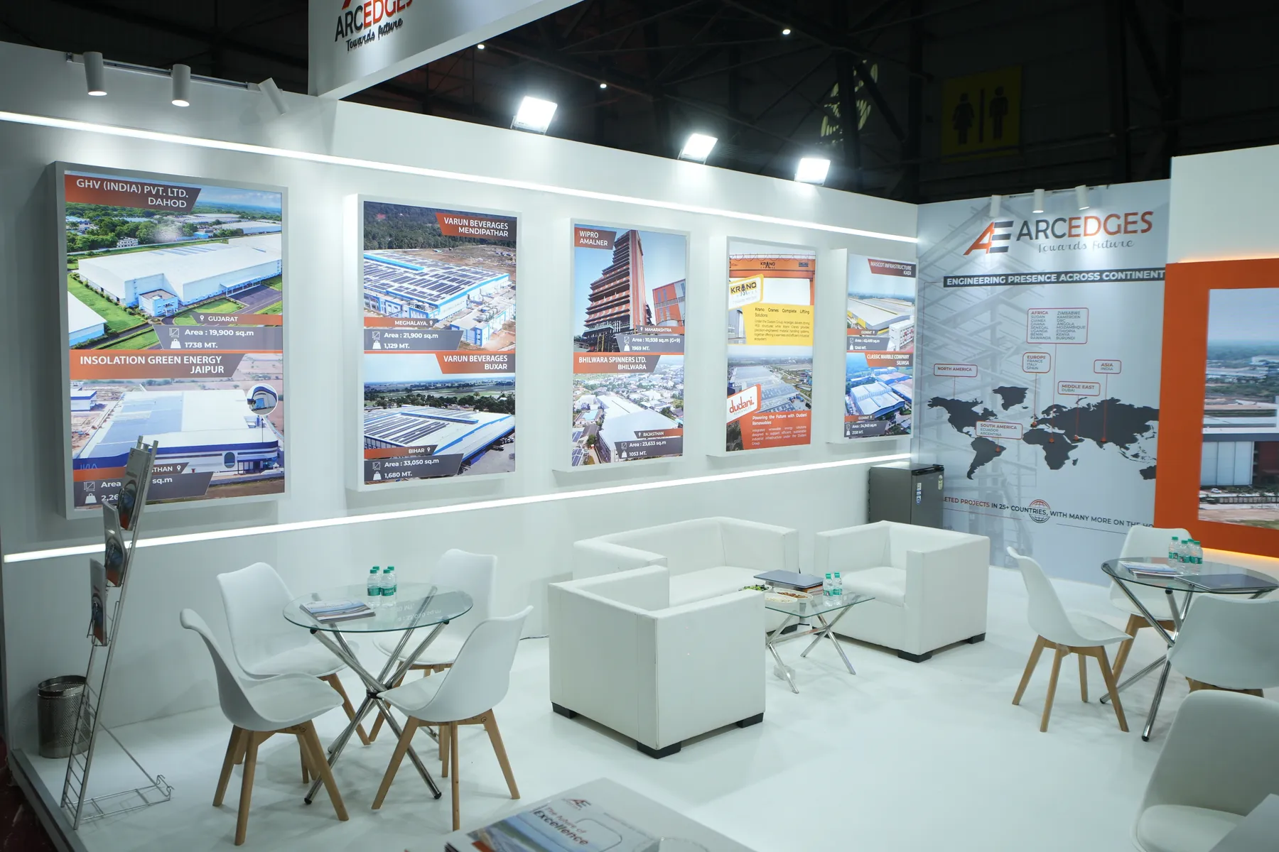 An Arcedges Building India LLP exhibition stall with lit project panels and reception desk.