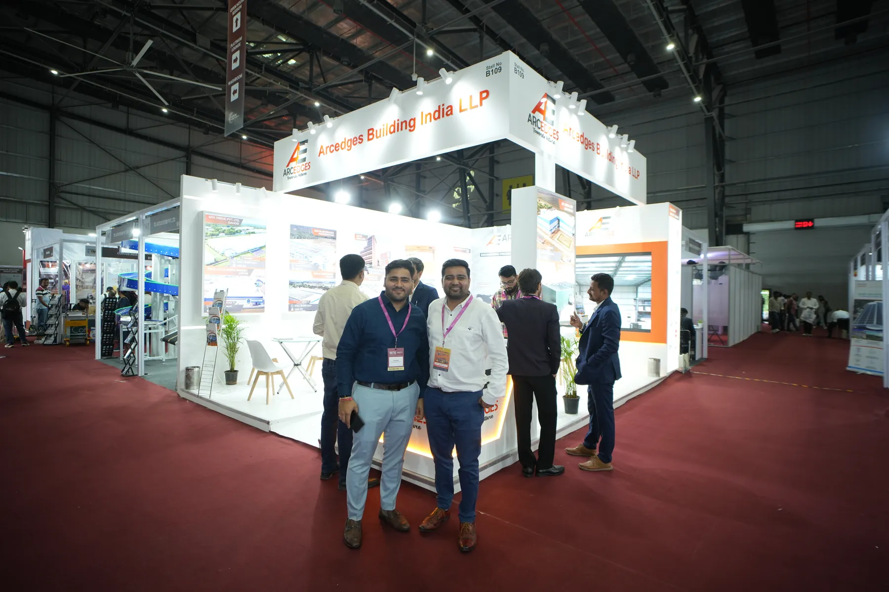 An Arcedges Building India LLP exhibition stall with lit project panels and reception desk.