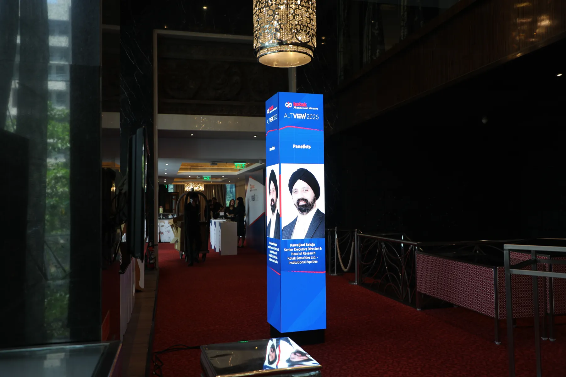 A tall digital kiosk showing a panelist profile at the ALTVIEW 2026 lobby.