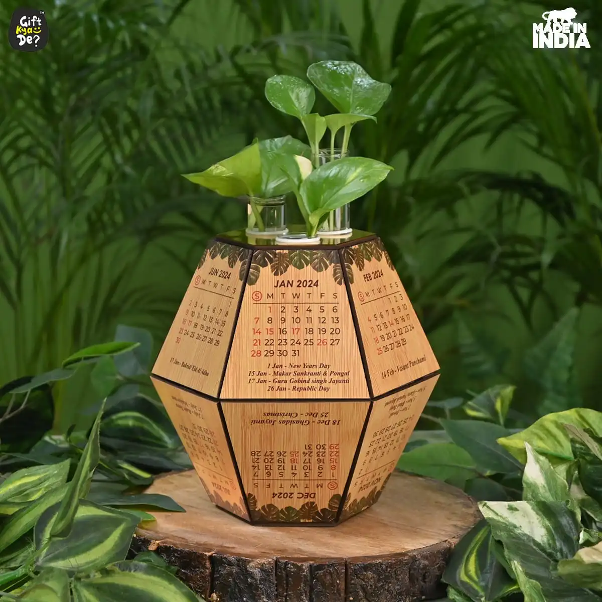 A wooden dodecahedron desk calendar with a small plant set in greenery.