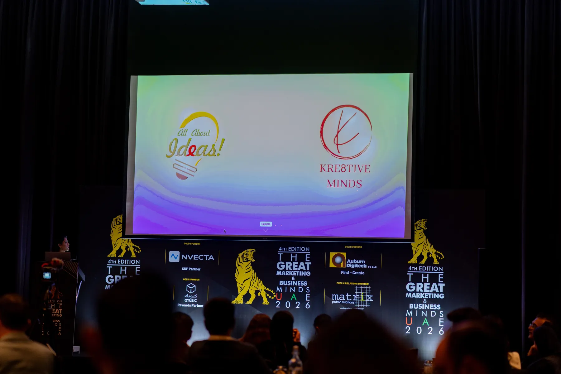 A conference stage screen showing the Kre8tive Minds logo at Great Marketing and Business Minds UAE 2026.