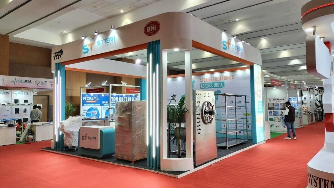 A white and teal STERI branded exhibition booth with glass display cabinets in a trade-show hall.