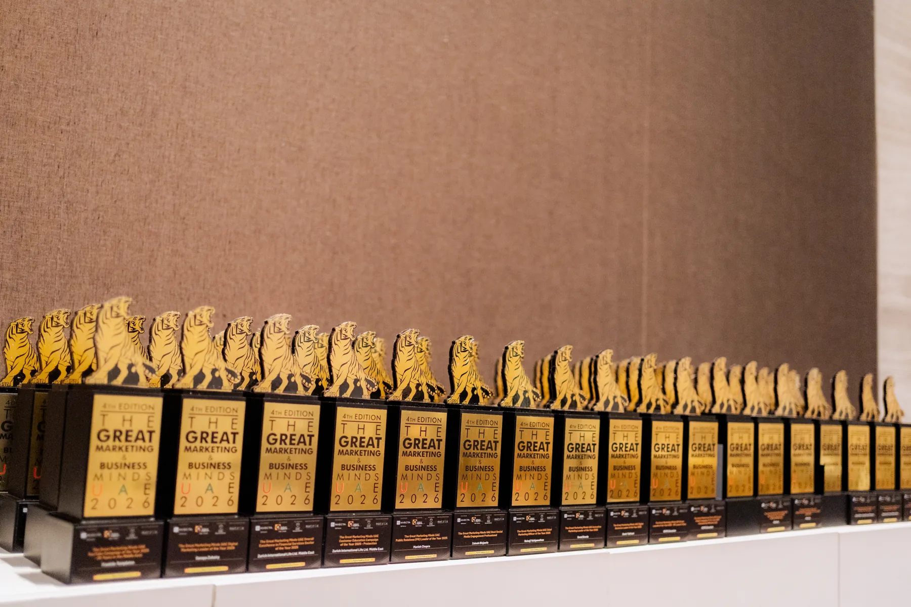 A long row of identical black-and-gold corporate award trophies arranged against a draped backdrop.