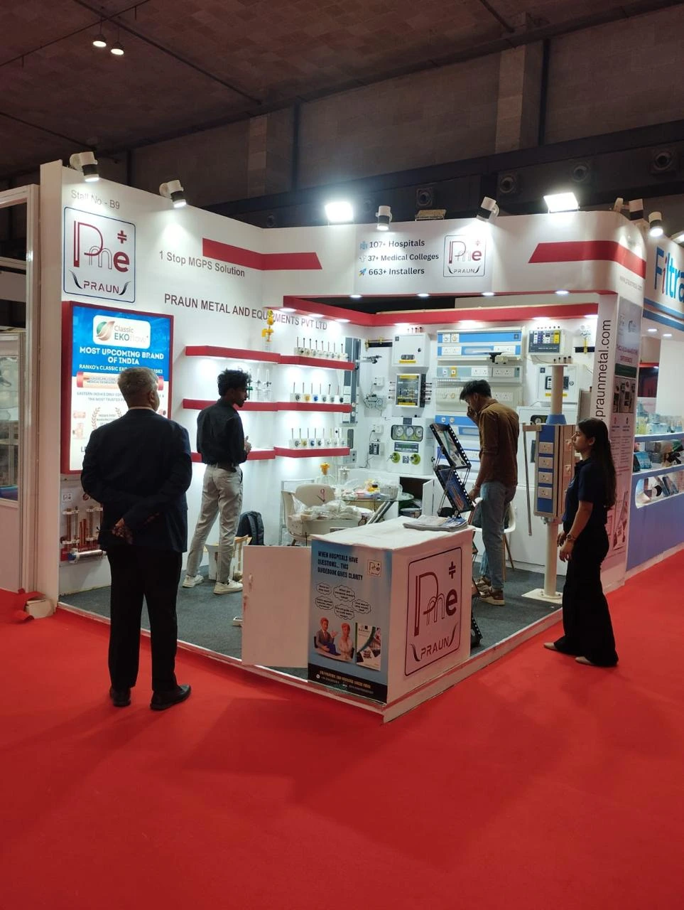 Visitors browse the Praun Metal and Equipment exhibition booth with product shelving.