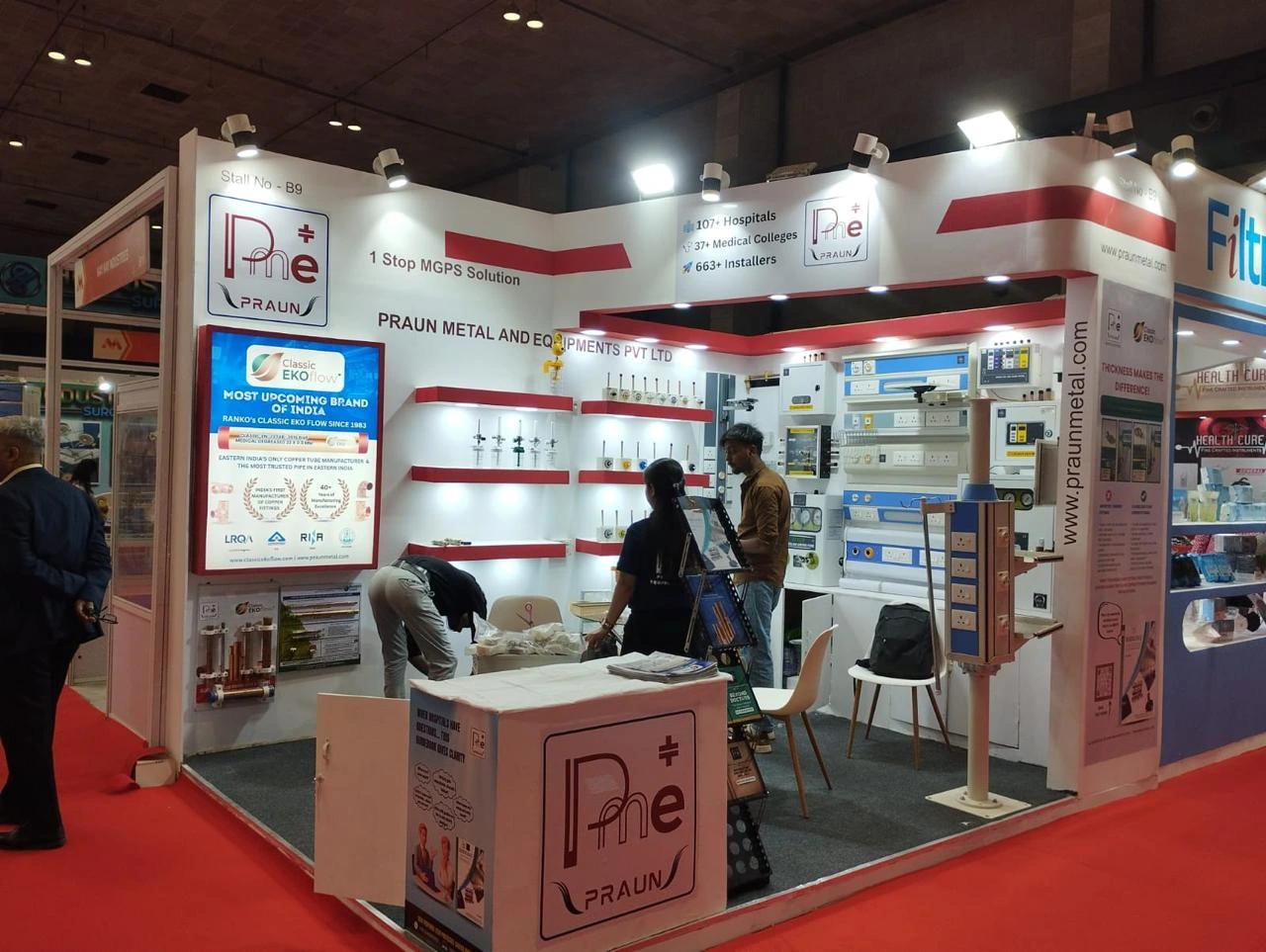 The Praun Metal and Equipment exhibition booth showing product shelving and staff at a trade show.