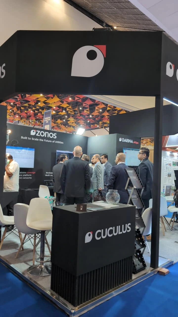 A corner view of the black Cuculus exhibition booth with a reception counter and lounge seating.