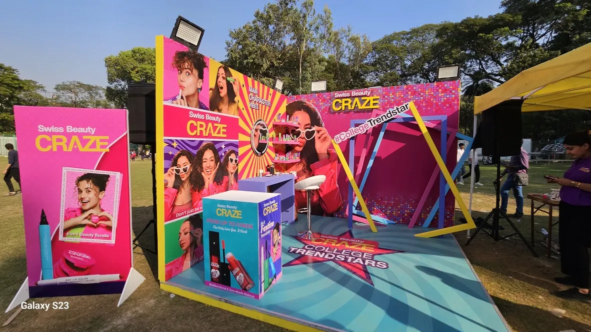A vibrant pink Swiss Beauty Craze College Trendstars experiential booth on an outdoor field.