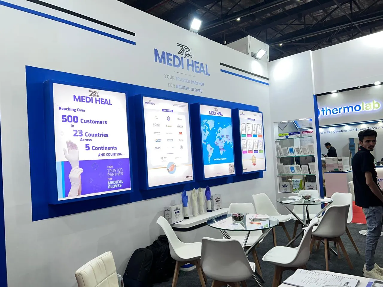 The Medi Heal exhibition booth with backlit panels citing 500 customers across 23 countries and product displays.