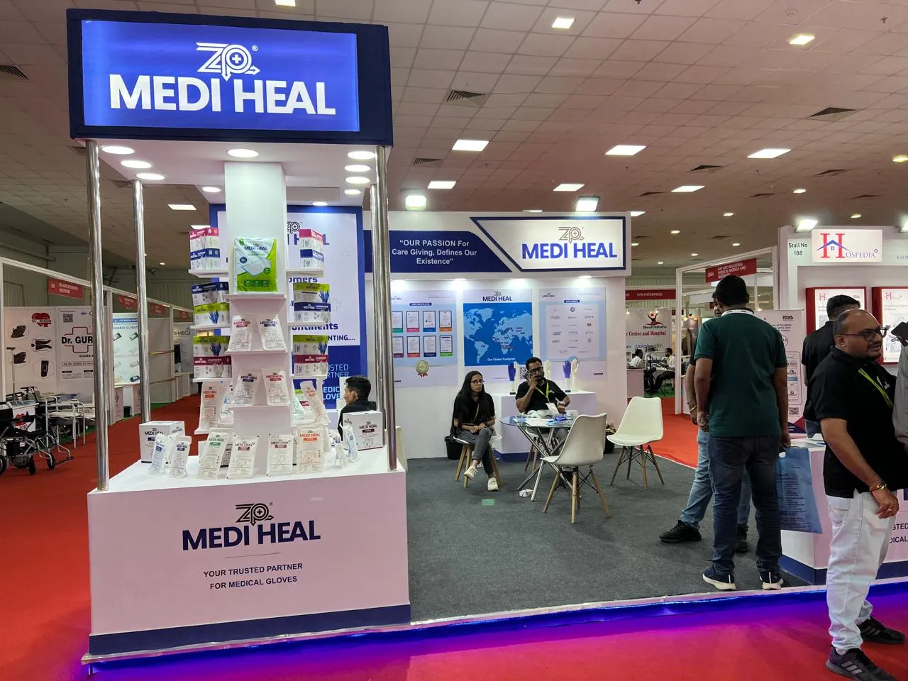 A Medi Heal exhibition booth with a stacked product display tower and visitors under an illuminated blue sign.